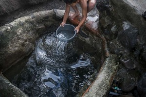 Un niño recoge agua contaminada de un pozo de superficie.